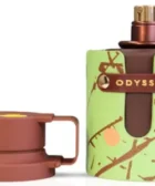 odyssey dubai chocolat: Botella marrón con difusor expuesto y tapa retirada, envuelta en funda verde con ramas y frutas ilustradas.